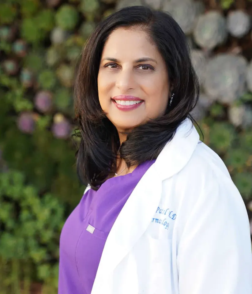 Dr. Nita Patel in a white coat and purple scrubs.