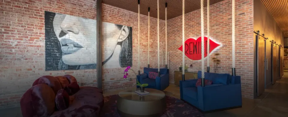 Rewind Aesthetics lounge with brick walls, seating, and the red Rewind lips sign.