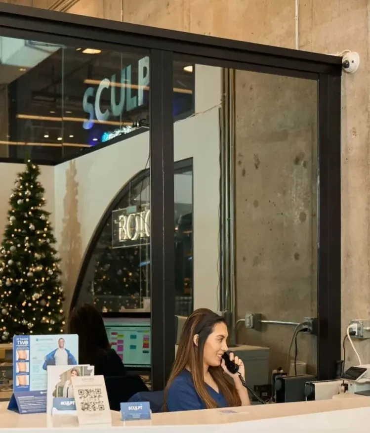 Reception desk at Sculpt DTLA, with Sculpt signage and The Bloc reflected behind the desk.