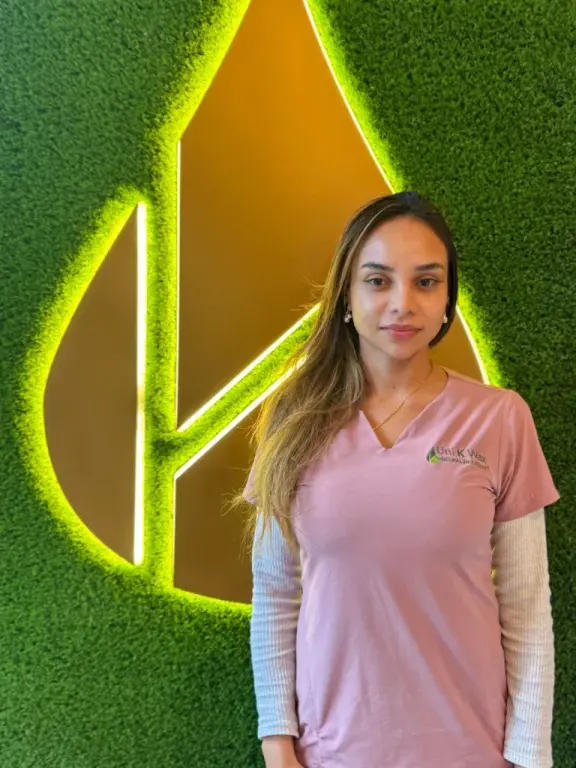Staff member at Uni K Wax Studio, Brickell, in front of the branded leaf-logo wall
