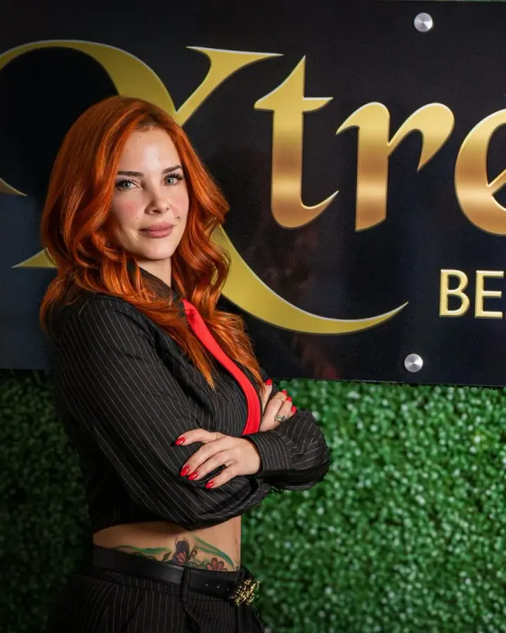 Mily, owner of Xtreme Beauty Salon, in front of the studio sign