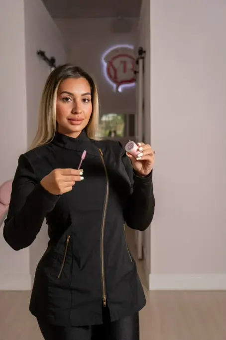 Jennyfer Osorio, founder of Your Brow Queen Spa, in the studio hallway with the brand's neon sign